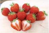 真っ赤なイチゴが9つ並んでいる、うち一つは縦に半分に切った状態で、断面がわかるように置かれている