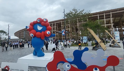 大阪・関西万博会場。赤と青の万博マスコットキャラクター「ミャクミャク」と来場者が行き交う広場